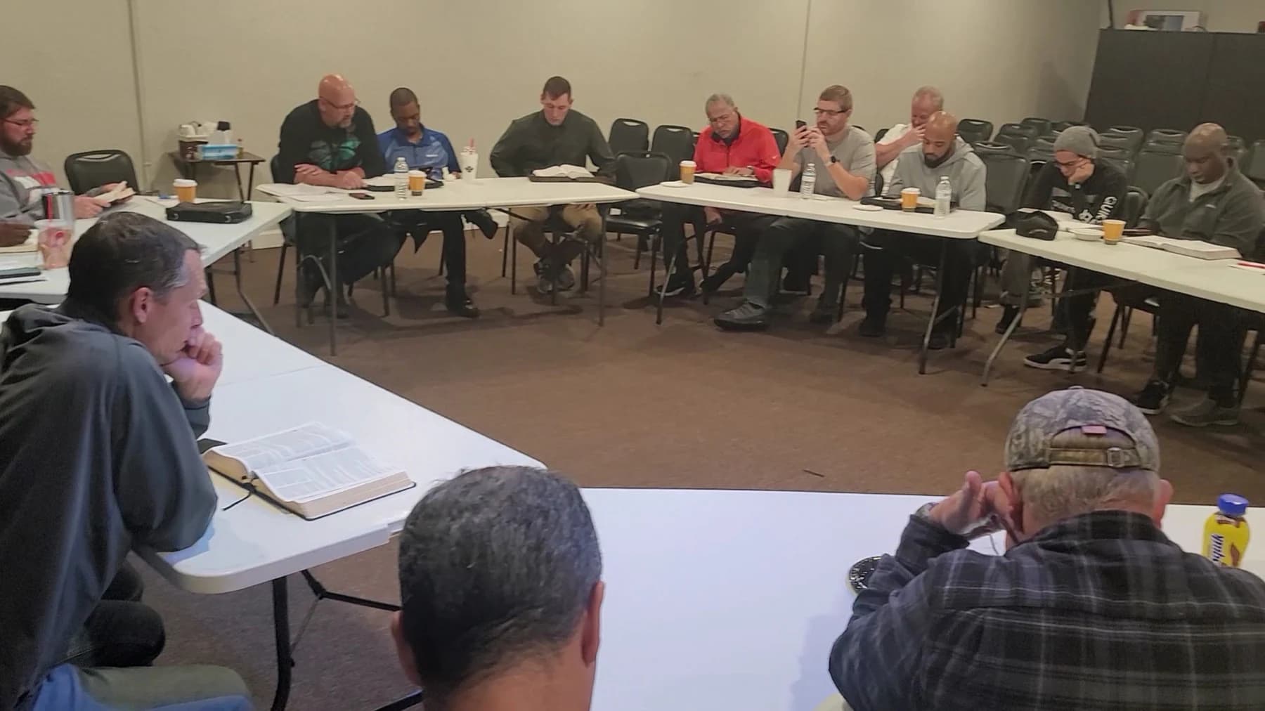 Men gathered around open Bibles during a Living Message Church study.